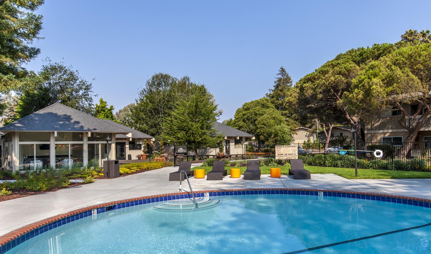 a swimming pool with a building and trees in the background